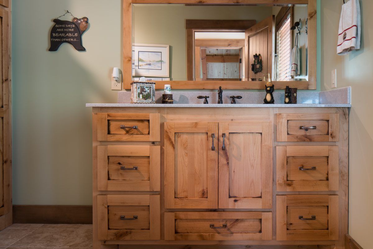 A bathroom with a sink, mirror, and wooden cabinets.