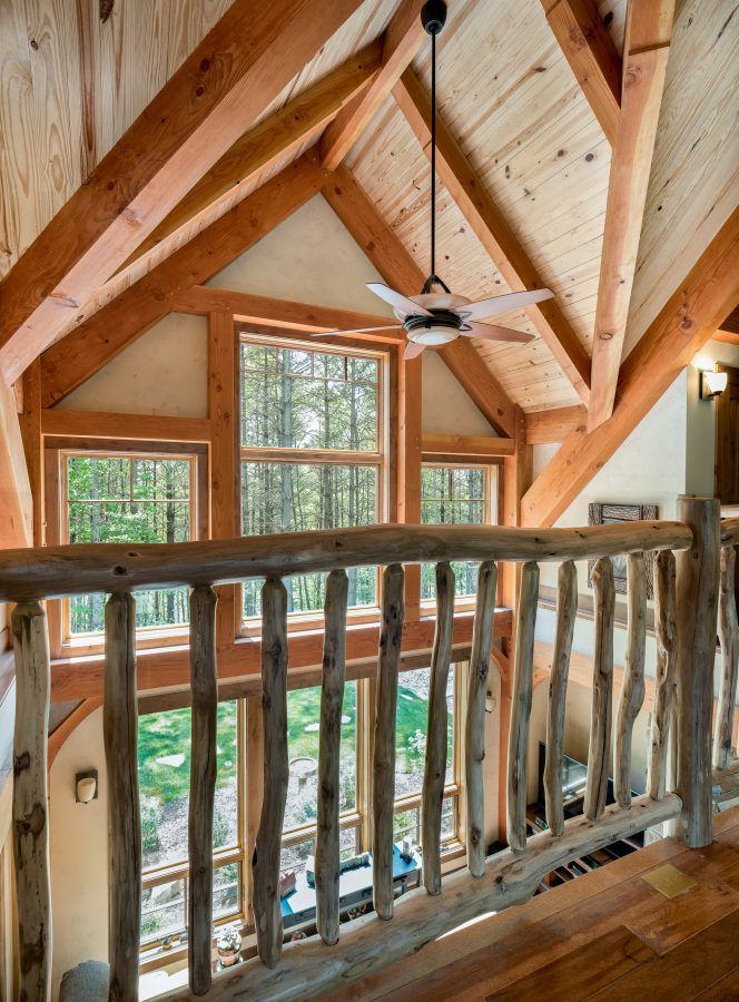 A wooden railing in a house with a ceiling fan.