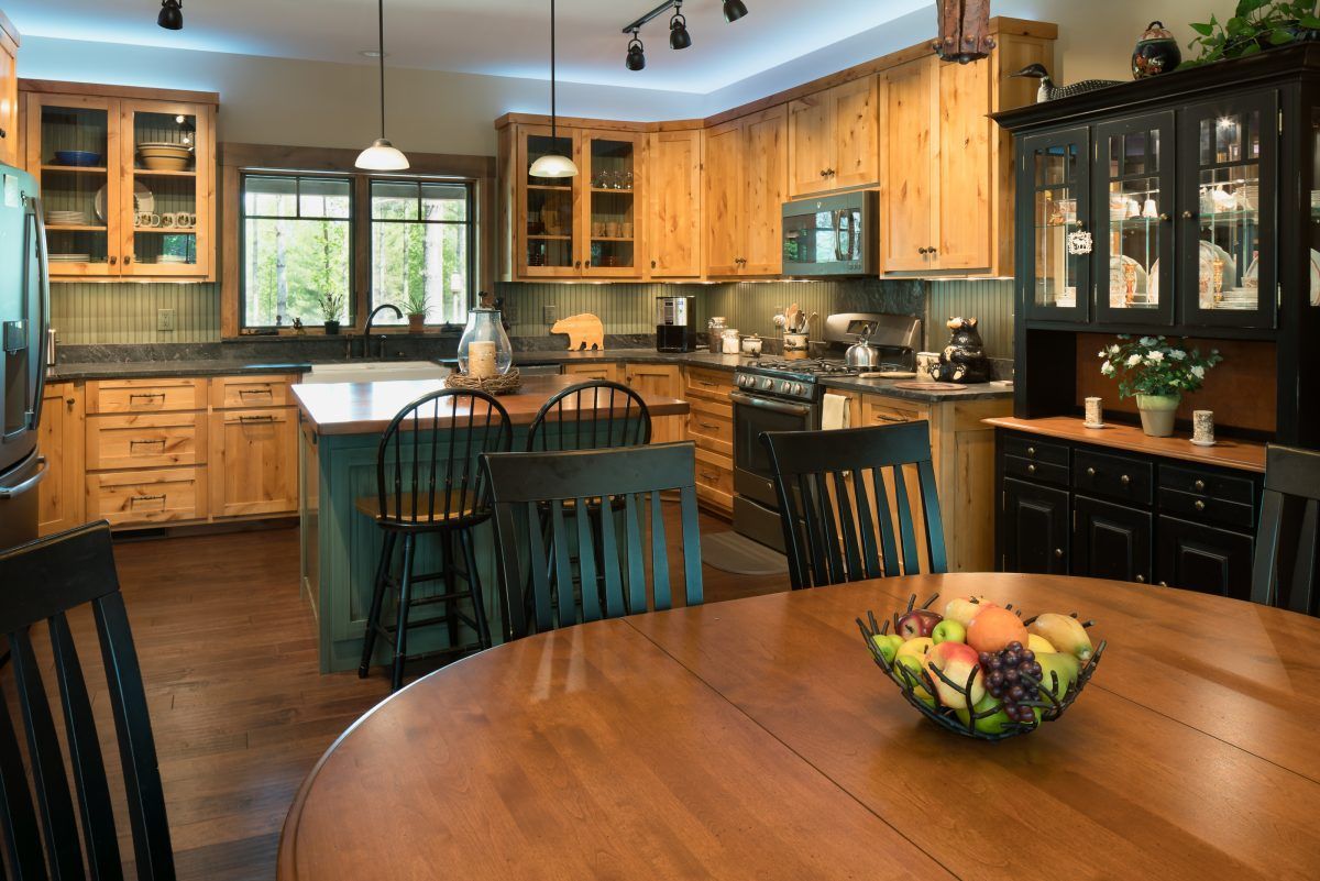 There is a bowl of fruit on the table in the kitchen.