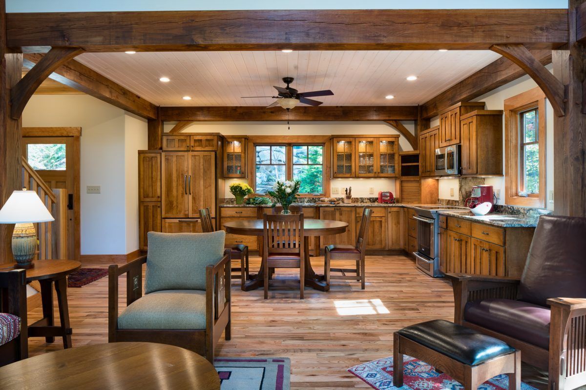 A living room with a table and chairs and a kitchen in the background.
