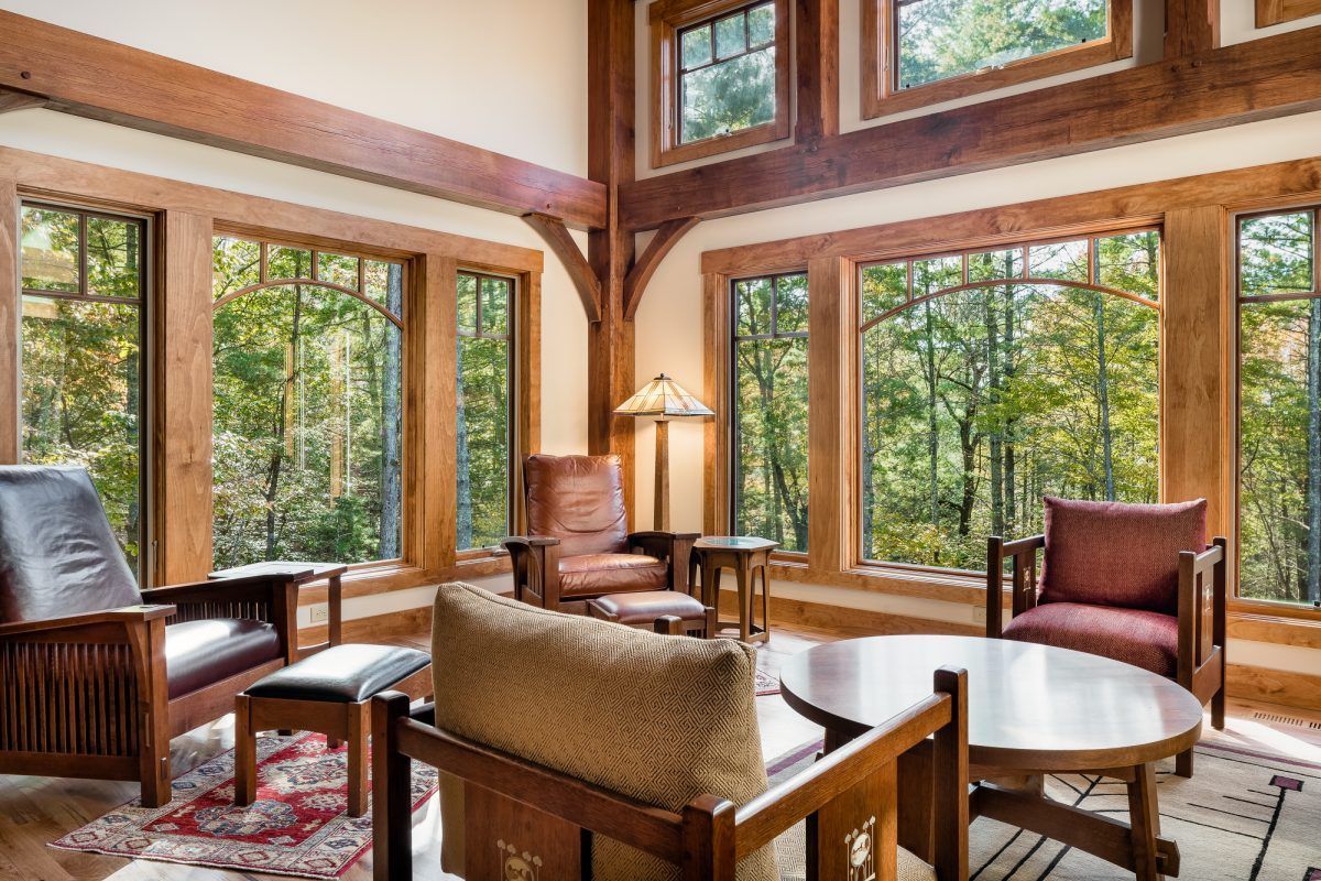A living room with a lot of windows and wooden furniture.