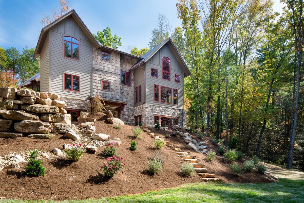 A large house is sitting on top of a hill in the middle of a forest.