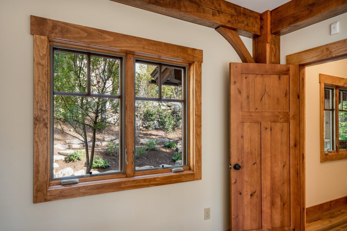 A bedroom with two windows and a wooden door.