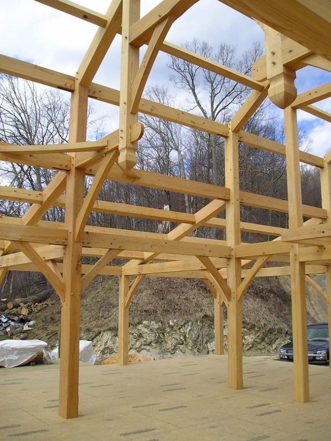 A large wooden structure is being built with trees in the background.