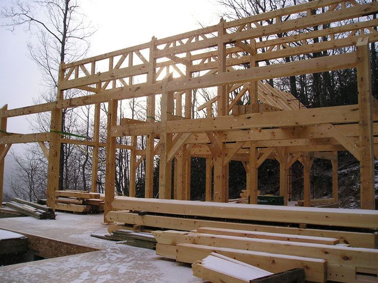 A large wooden structure is being built in the snow.