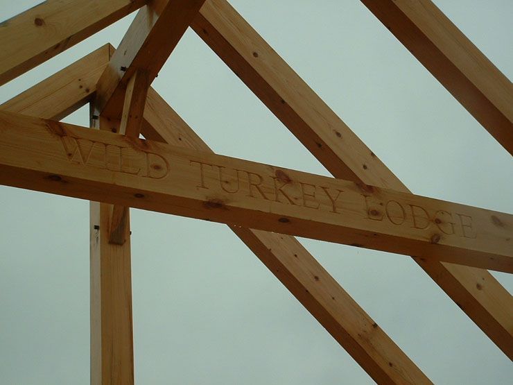 The word wild turkey is carved into a wooden structure.