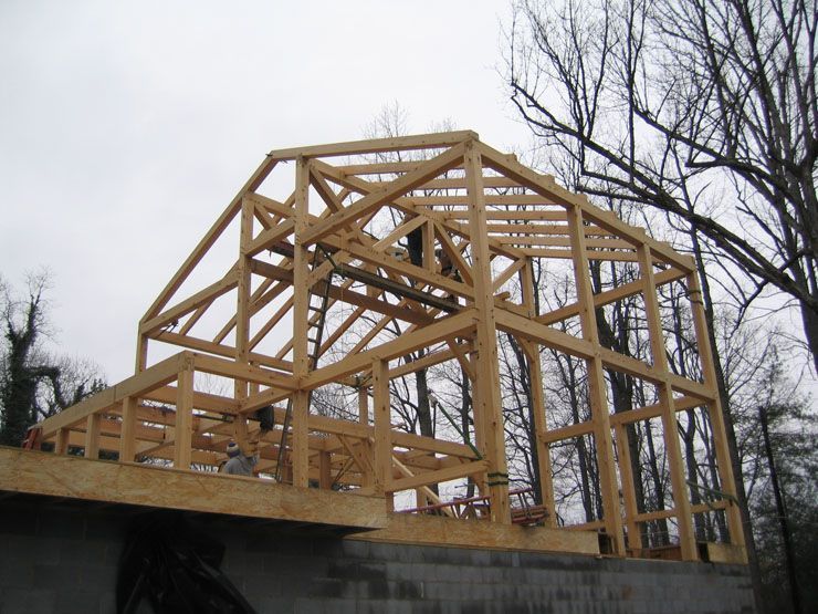 A wooden structure is being built with trees in the background.