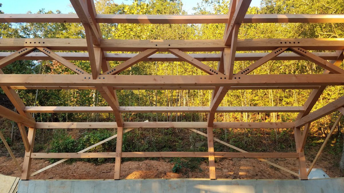 The ceiling of a wooden structure with trees in the background.