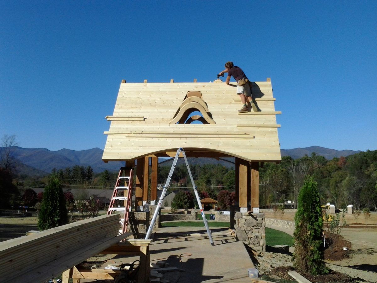 A man is working on the roof of a wooden structure.