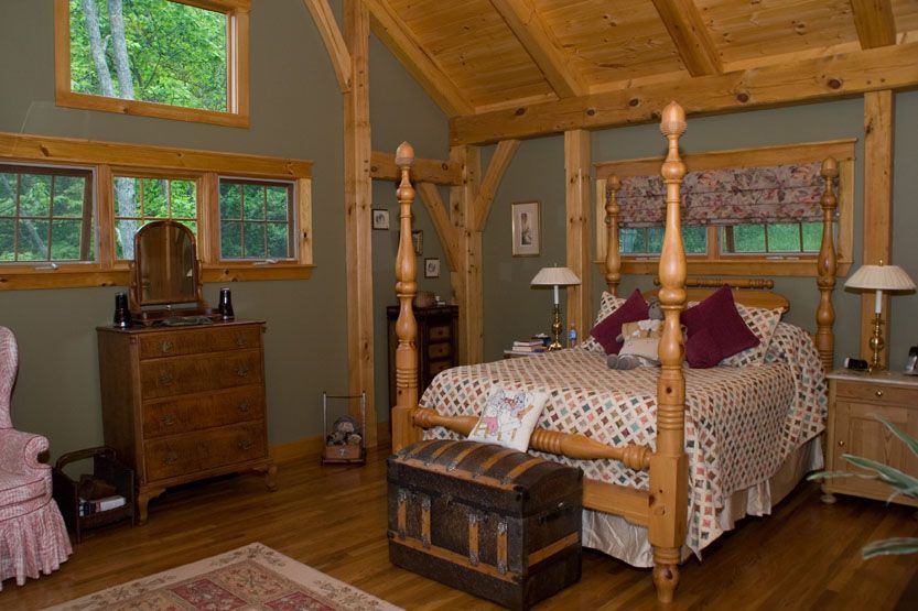 A bedroom with a four poster bed and a trunk on the floor.