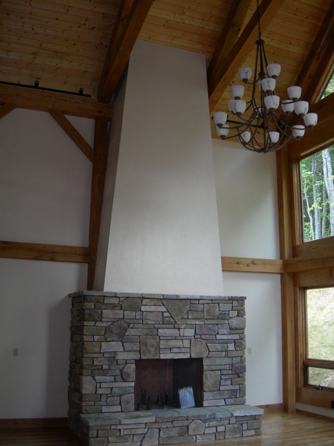 A living room with a stone fireplace and a chandelier.