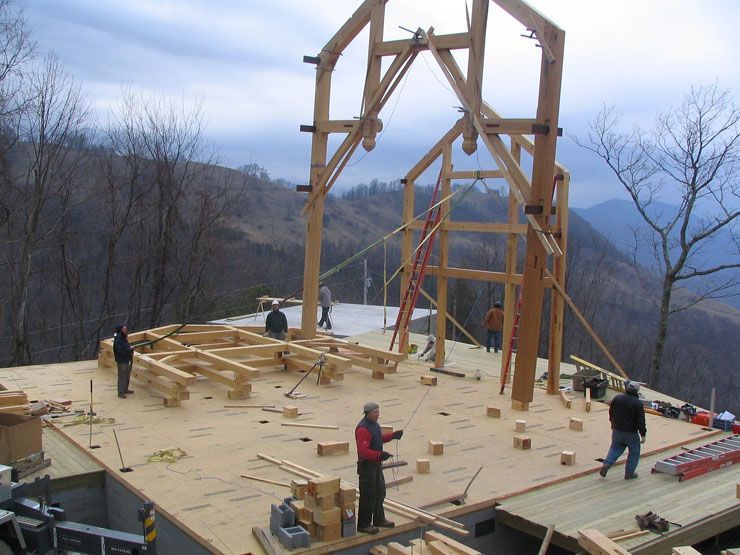 A large wooden structure is being built in the mountains.