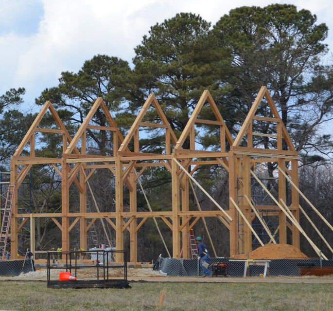 A large wooden structure is being built in a field.