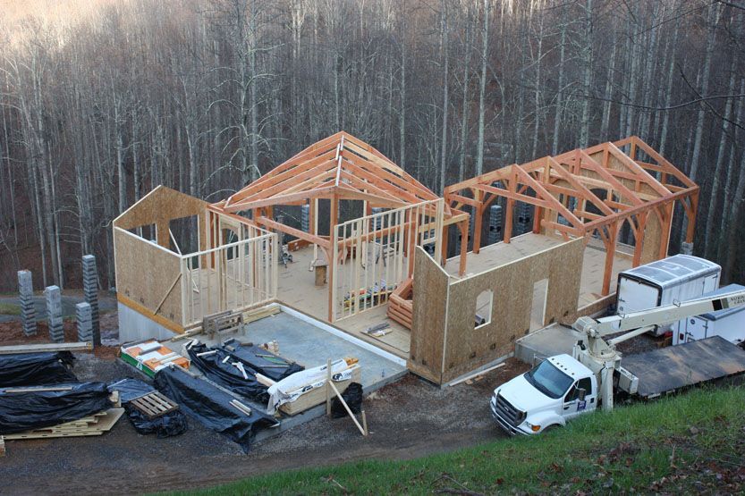 A white truck is parked in front of a house under construction.
