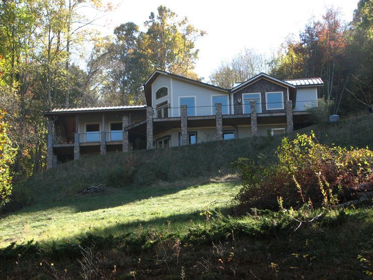 A large house sits on top of a hill surrounded by trees.