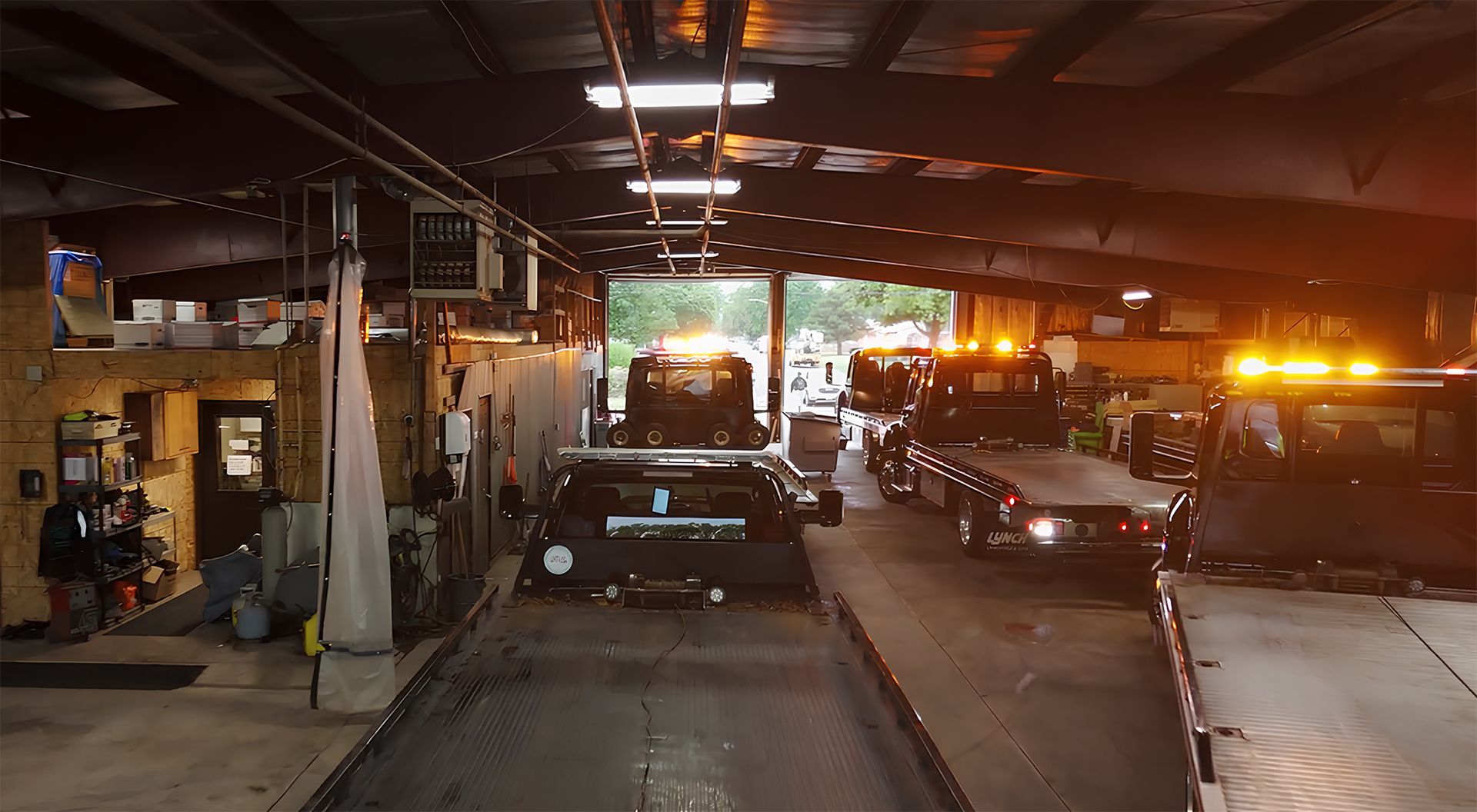 Tow trucks inside a garage with flashing amber lights.
