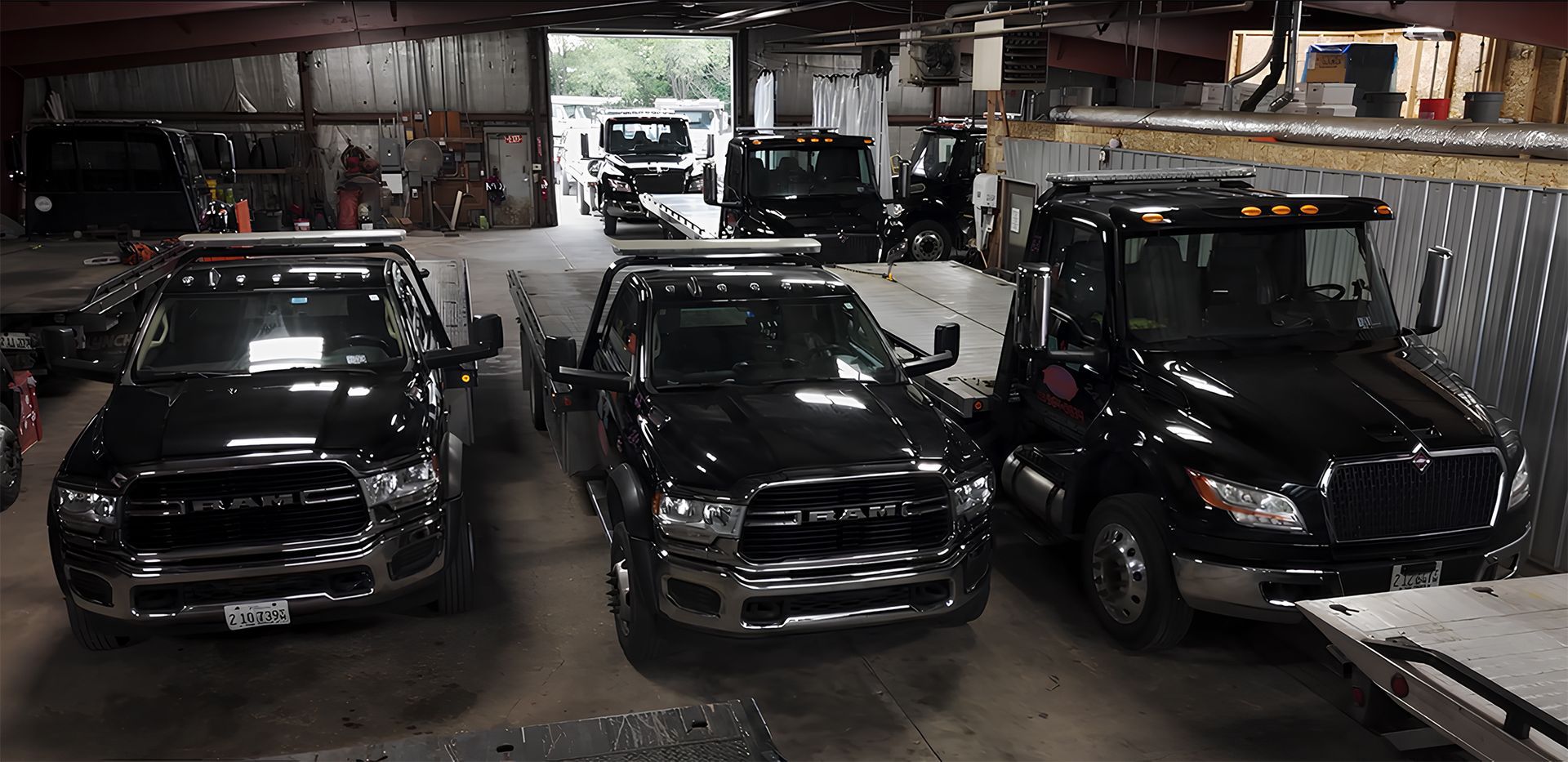 Several black tow trucks parked inside a garage.