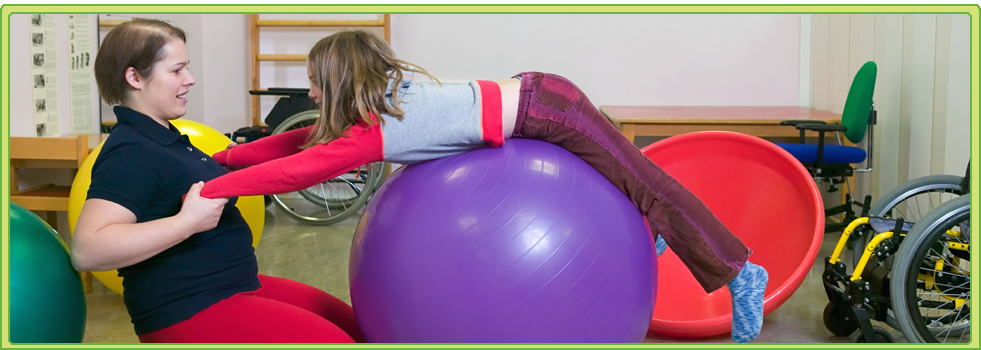 a woman assists a child on a purple exercise ball in a therapy room
