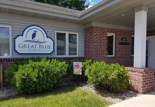 Great Blue Dental office exterior with sign, brick facade, bushes, and green grass.