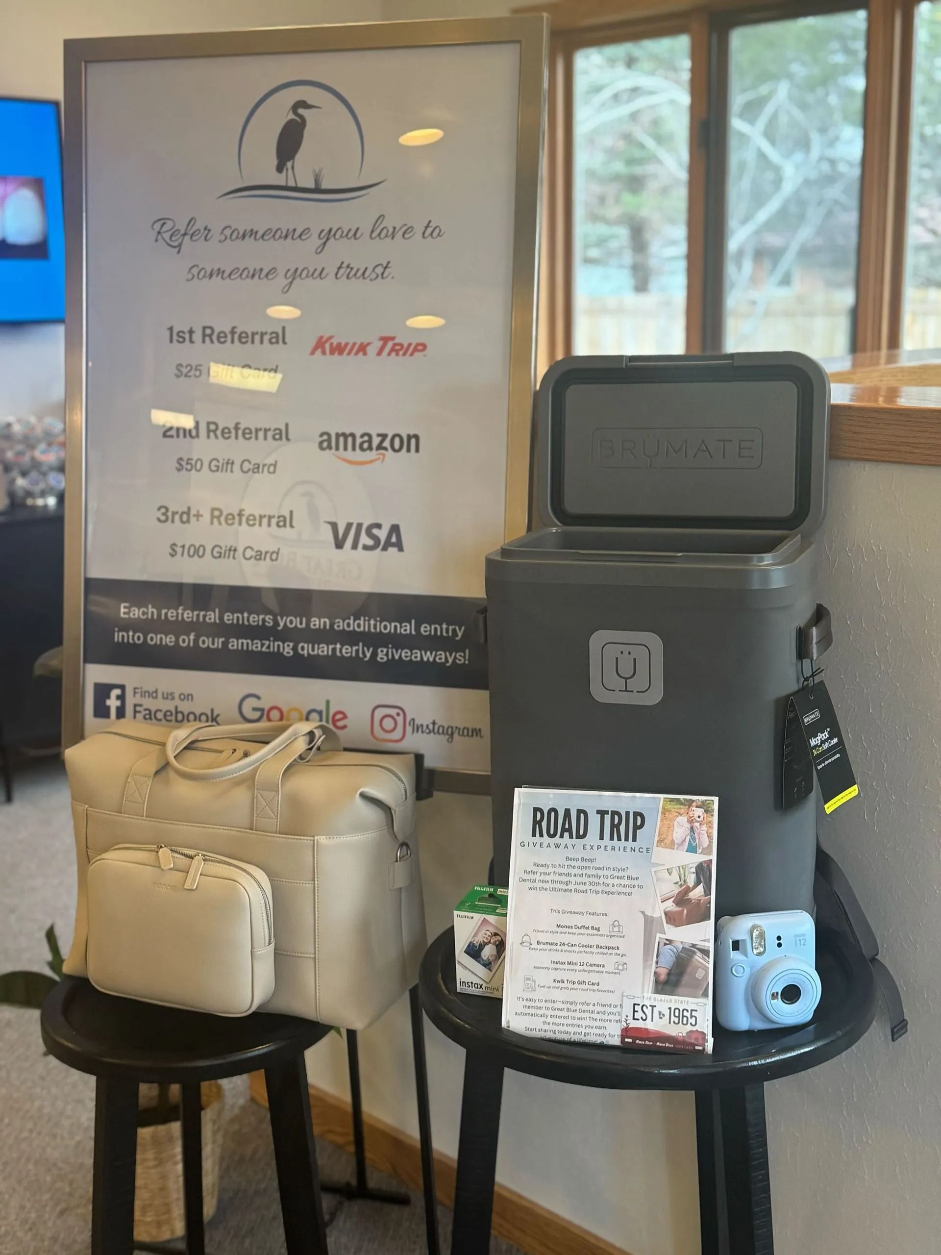 Display of prizes, including a cooler, bag, camera, and referral promotion sign.