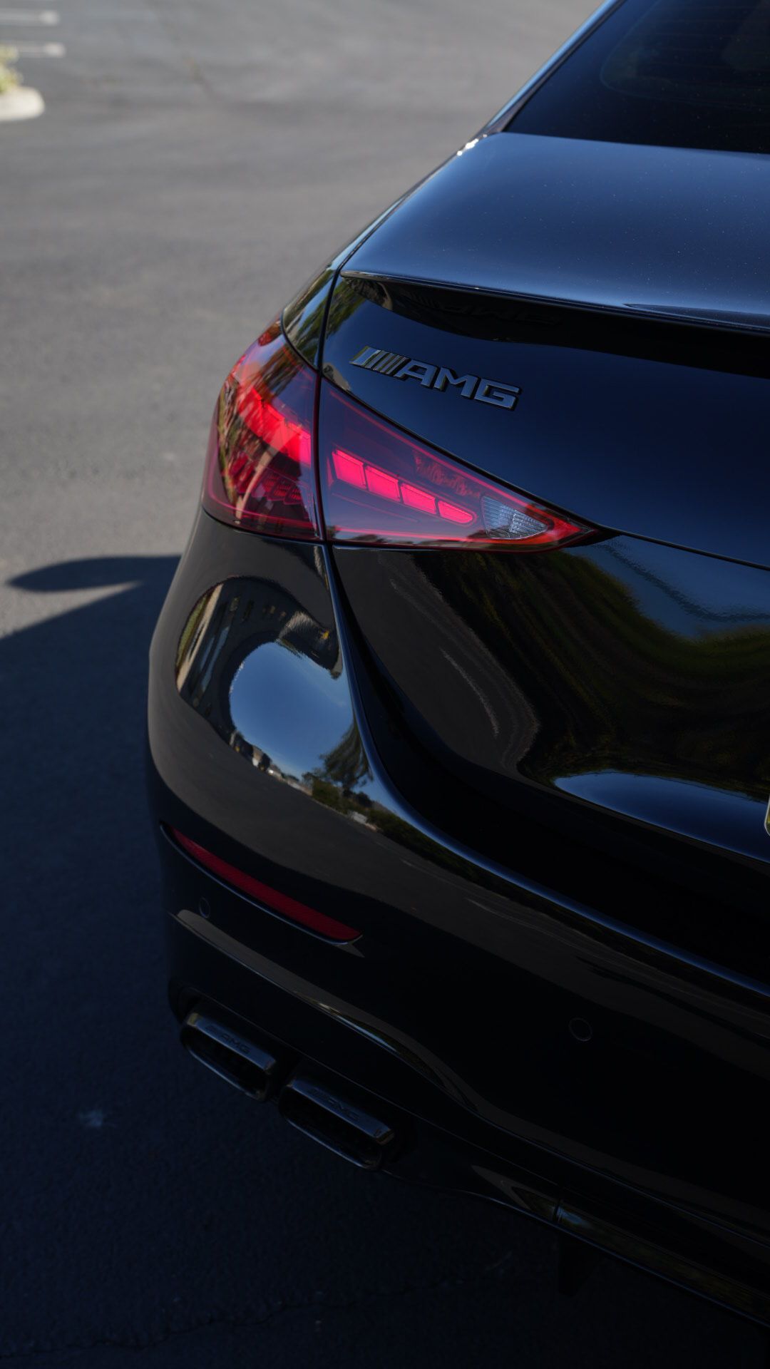 Rear view of a black car with red taillights on a paved road.