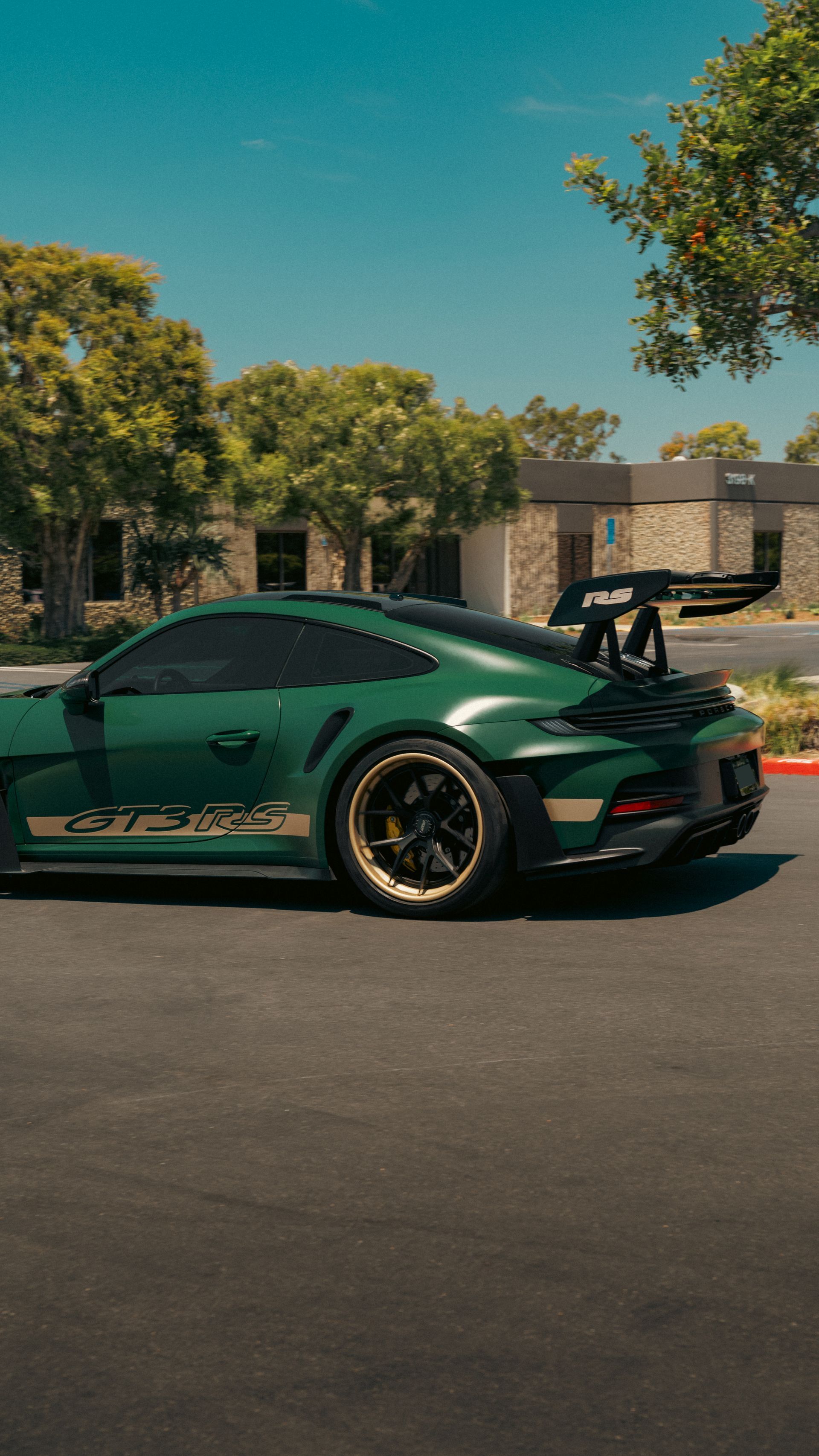 Green sports car parked on a street, with trees and houses in the background.