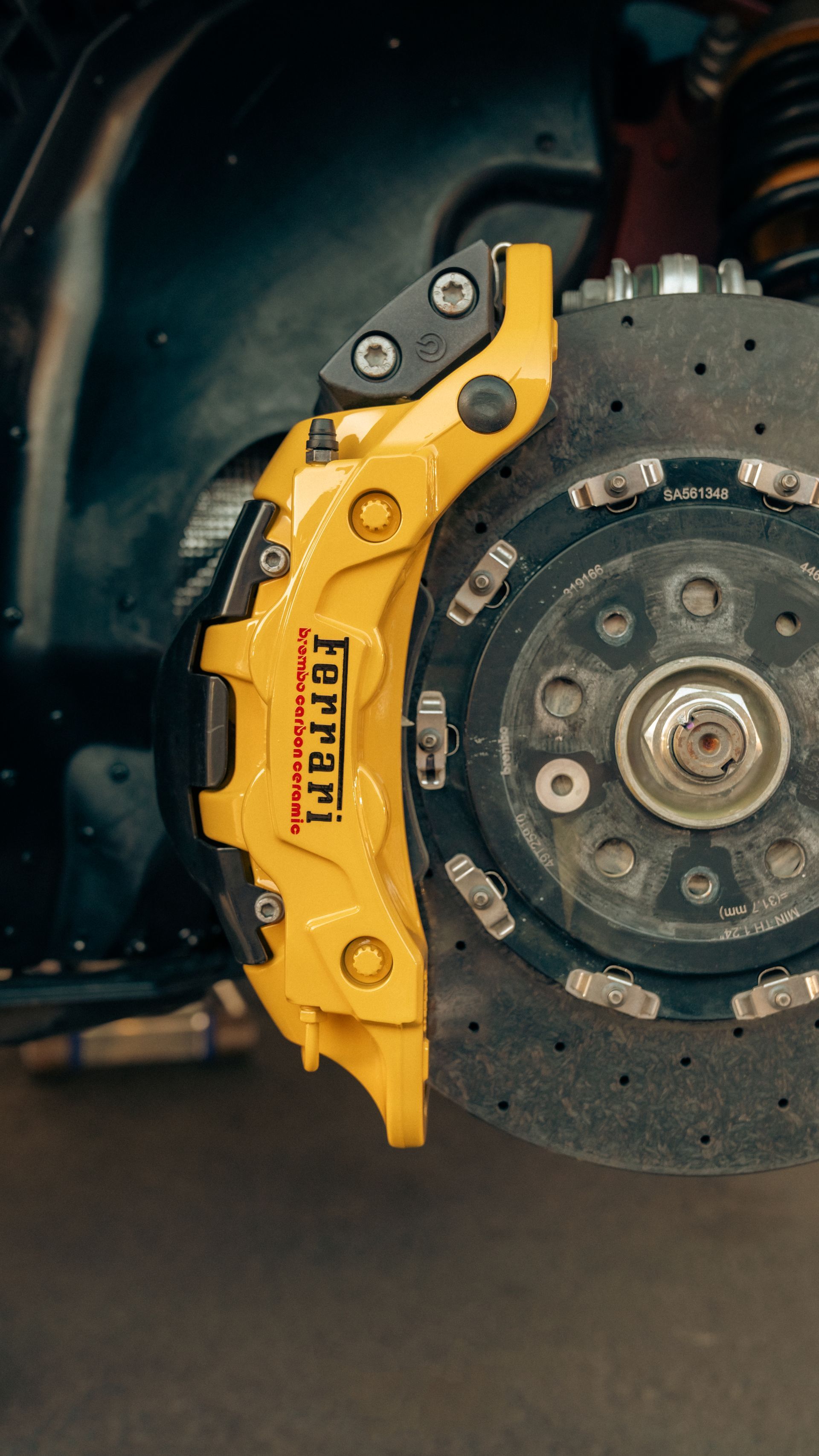 Yellow brake caliper on a car’s front wheel with visible disc rotor