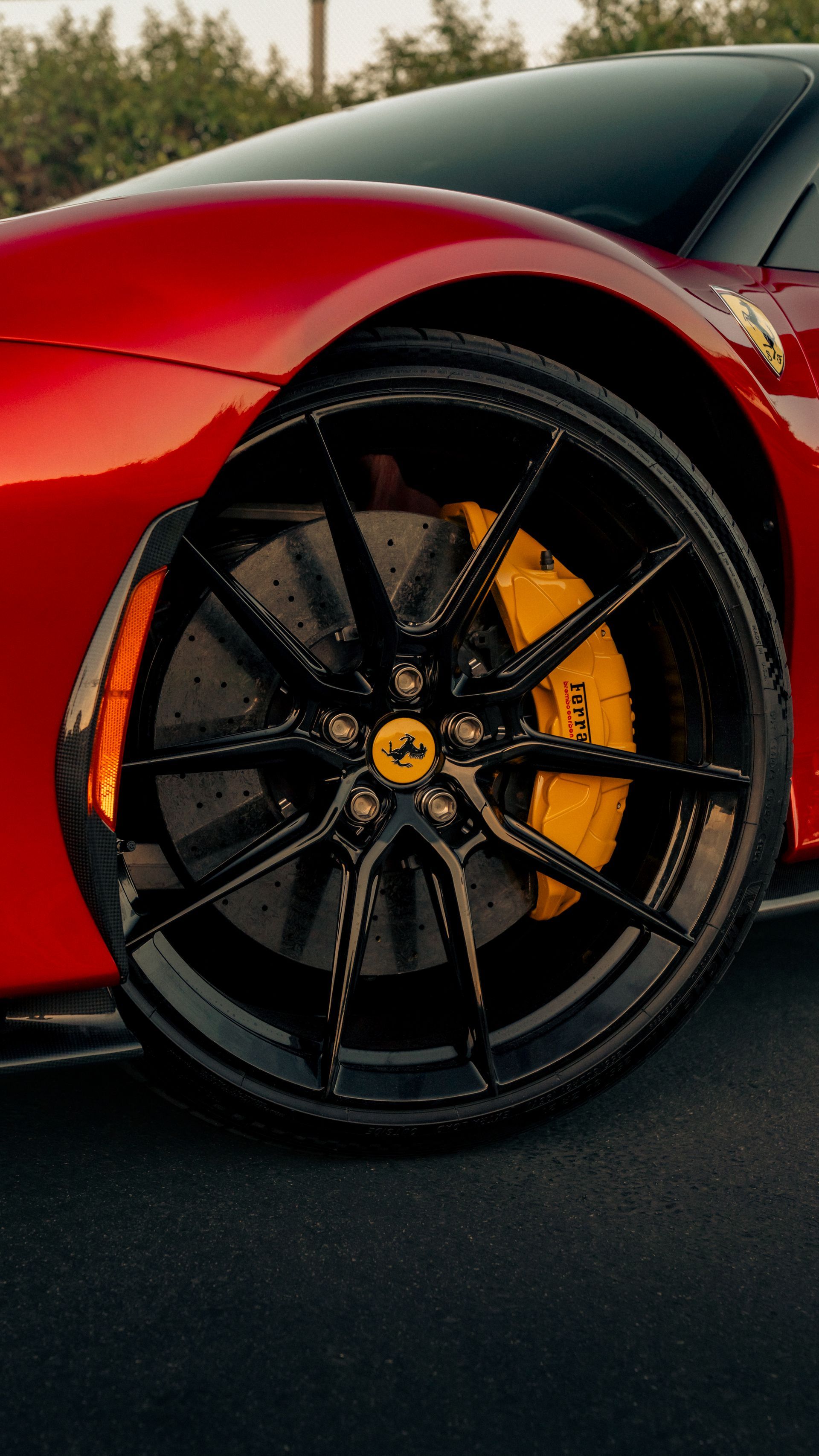 Close-up of a red sports car’s front wheel with black rim and yellow brake caliper.