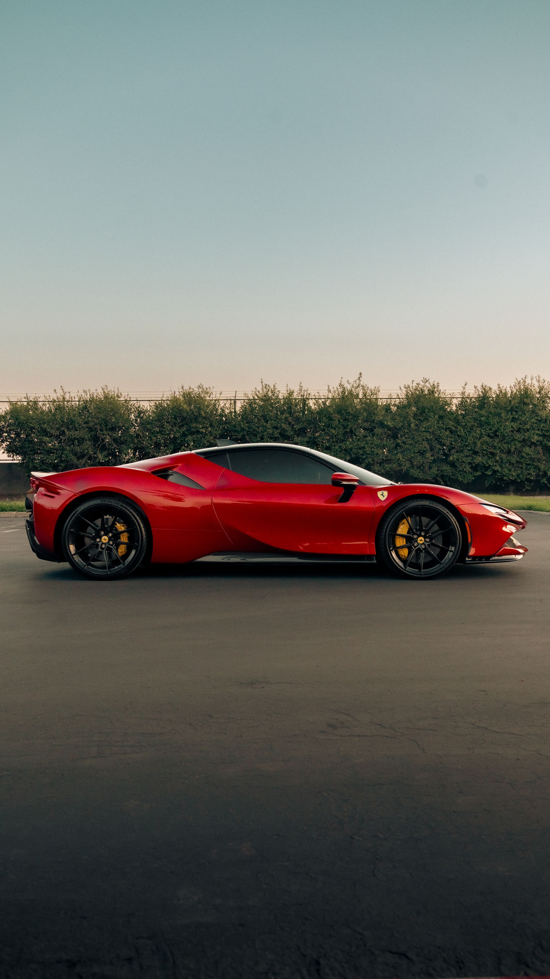 Red sports car parked on a road at sunset with trees in the background