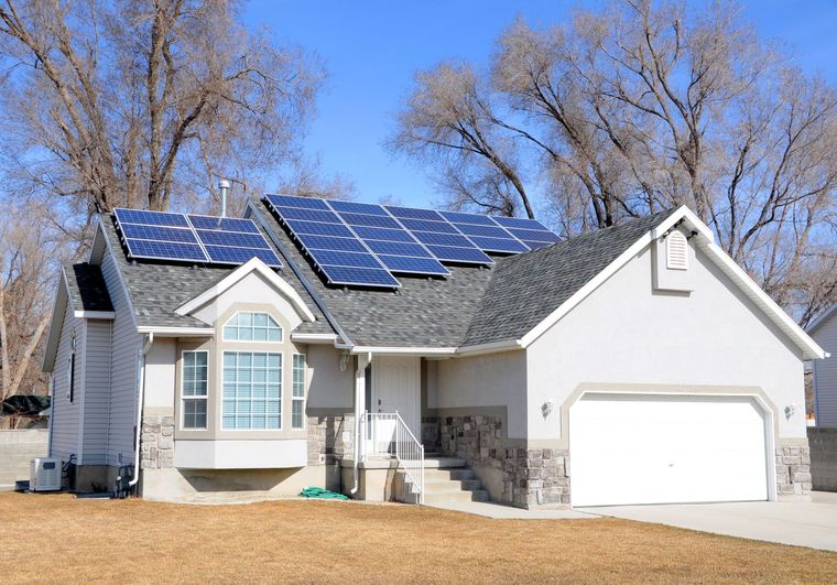 Single-story house with solar panels on the roof and a white truck parked in the driveway.