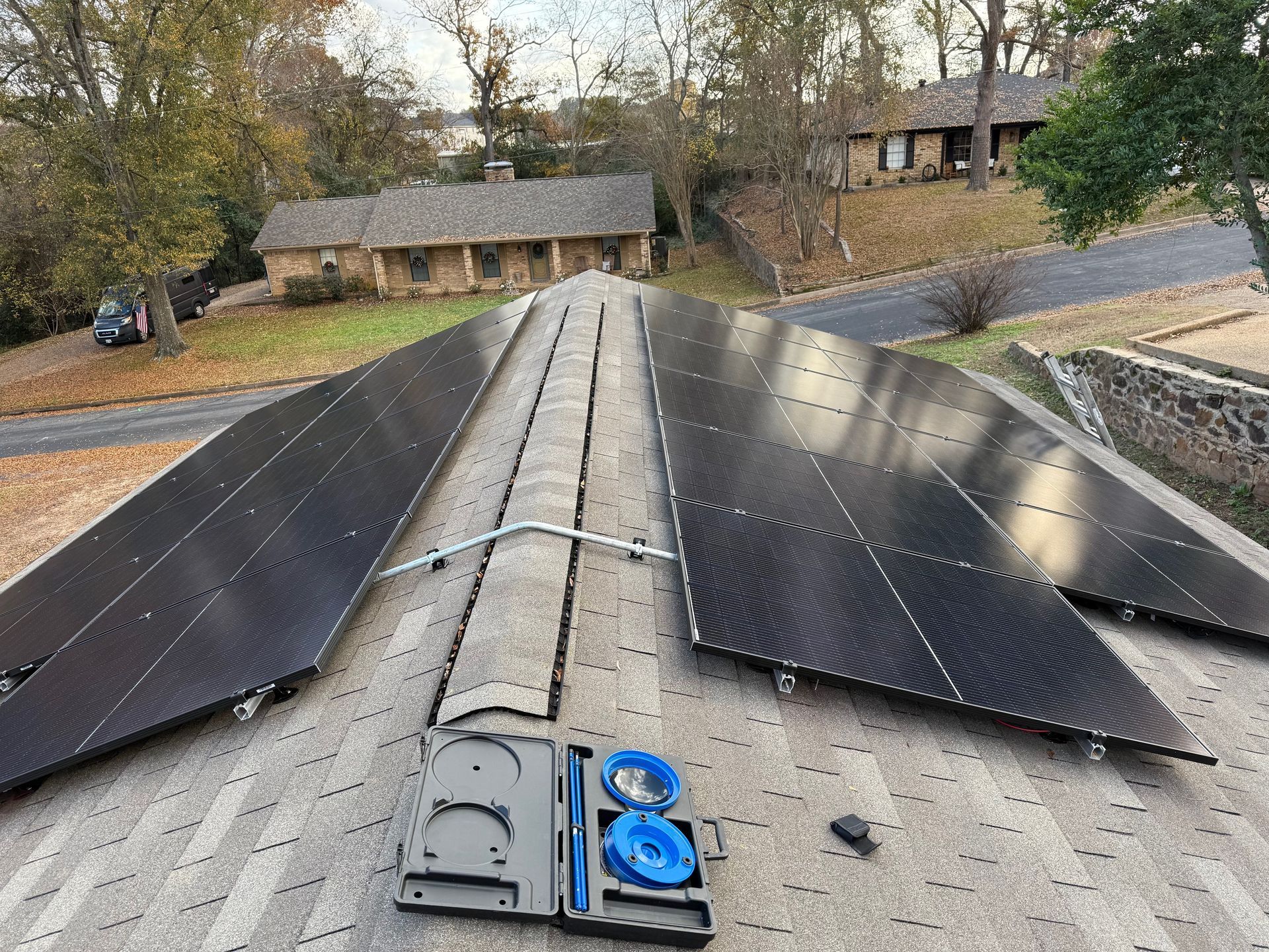 Solar panels installed on a residential roof with a tool case in the foreground.