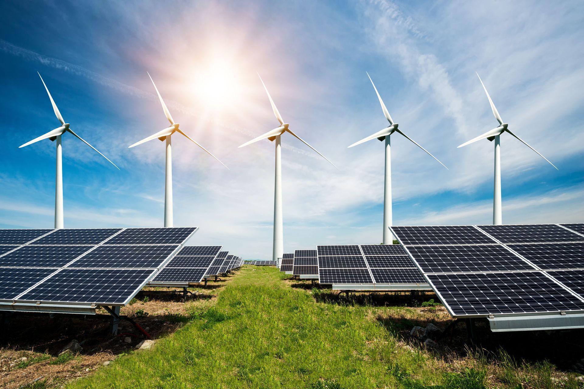 Solar panels and wind turbines in a green field under a bright sun