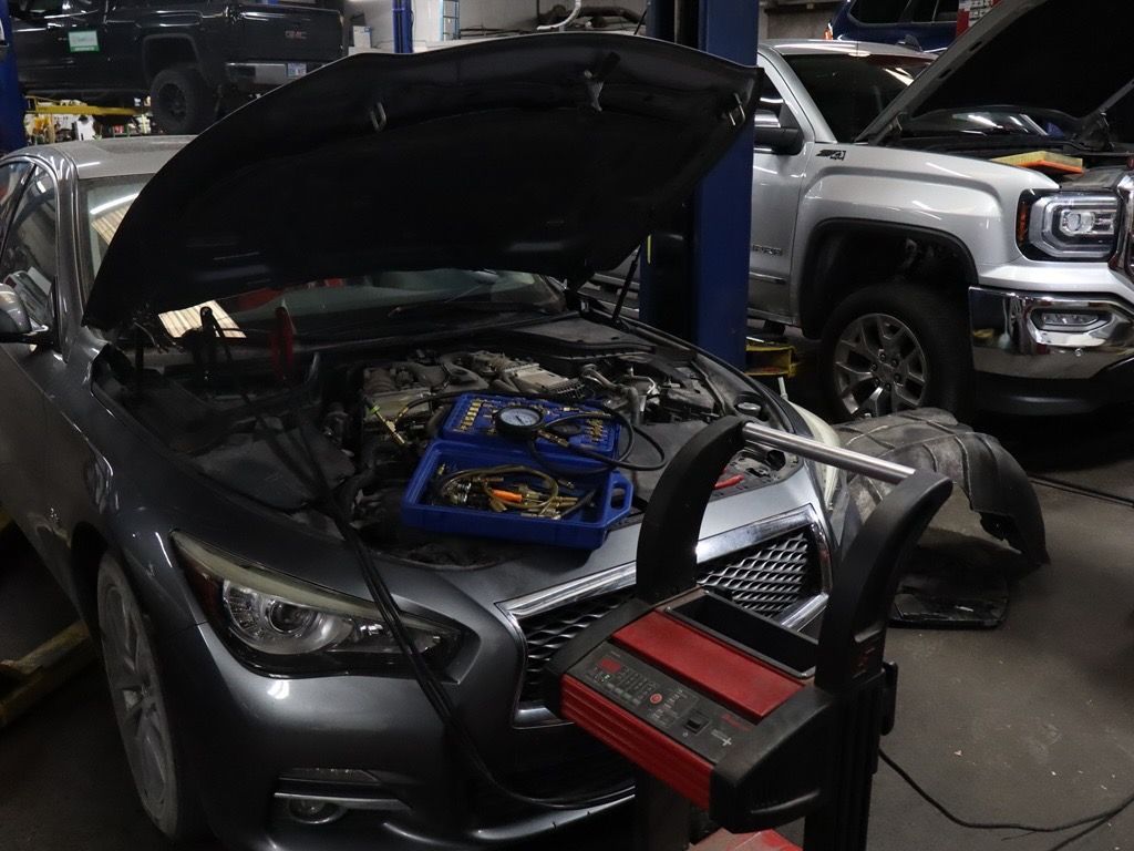 A car is being worked on in a garage with the hood open