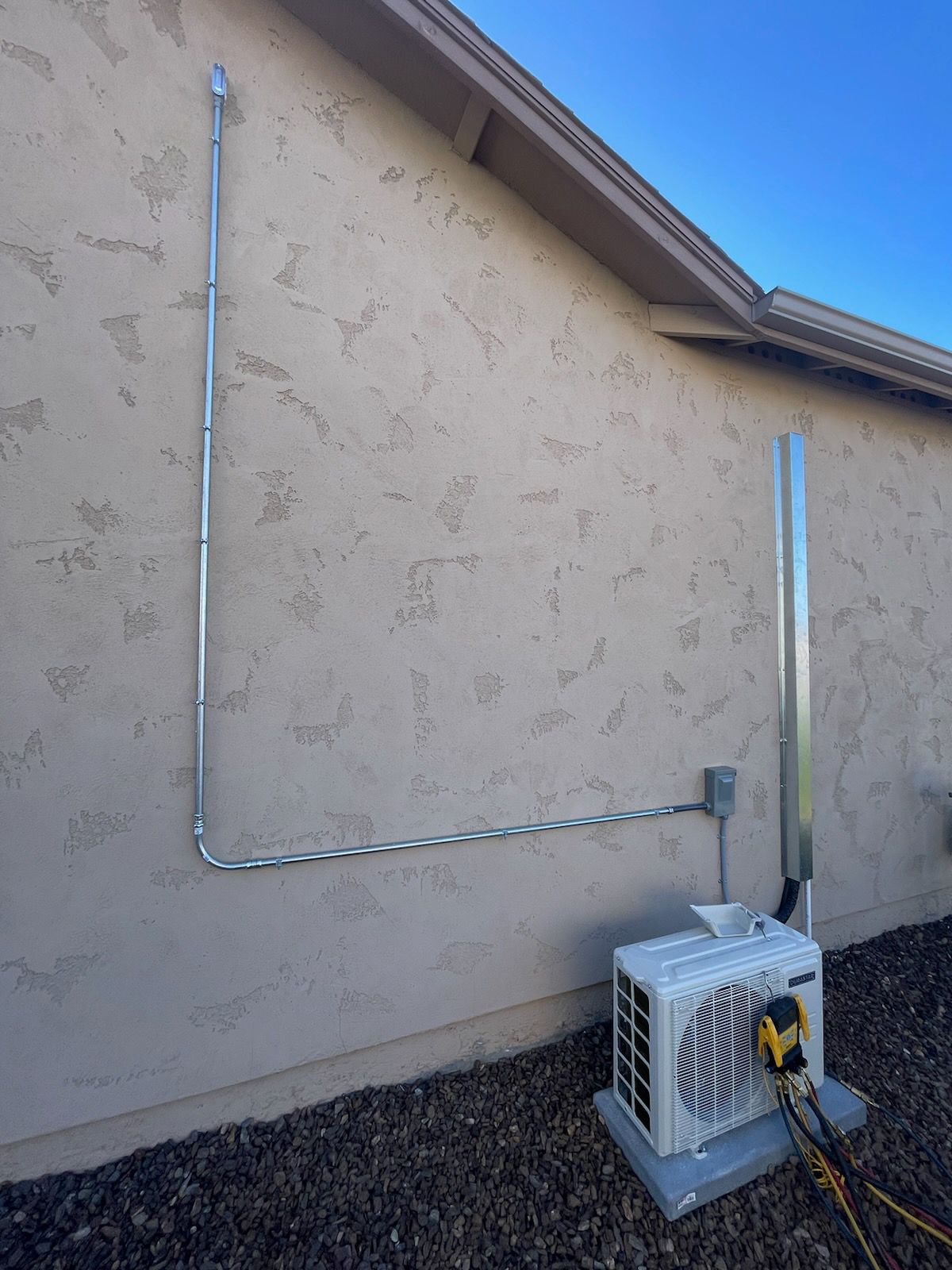 An air conditioner is attached to the side of a house.