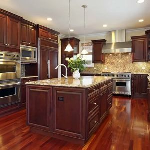 A kitchen with dark wood cabinets and island, granite countertops, stainless steel appliances, and hardwood floors.