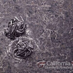 Two portions of dark noodles on a dark granite countertop with white veining.
