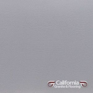 Gray, textured solid surface; a flooring sample with California Granite & Flooring logo.