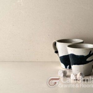 Two ceramic mugs with black brushstrokes and sugar cubes on a neutral-toned countertop.