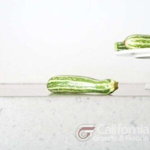 Zucchini on a light countertop. Two more zucchini on a white plate in the background.
