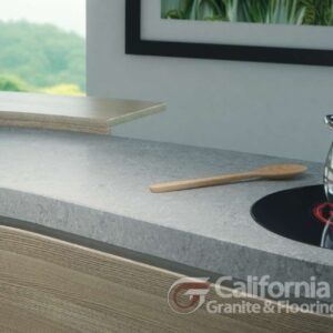 Kitchen countertop with a wooden spoon and a stovetop, next to a window with a view.