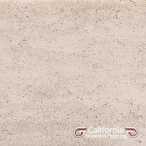 Cream-colored travertine stone tile, with a slightly mottled texture and some darker speckles.