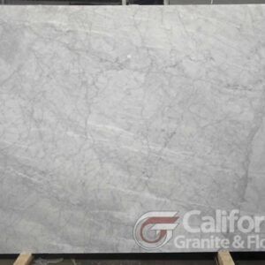 A large, light-gray marble slab with subtle veining and the California Granite & Flooring logo.