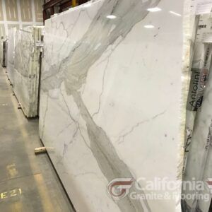 White marble slabs with gray veining displayed in a warehouse.
