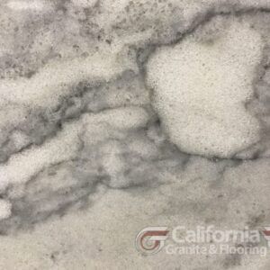 Close-up of white marble with gray veining, showing a cloudy pattern; California Granite & Flooring logo.