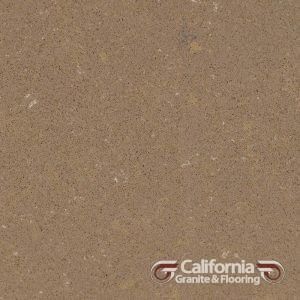 Close-up of tan-colored granite countertop with speckled pattern. California Granite & Flooring logo in corner.