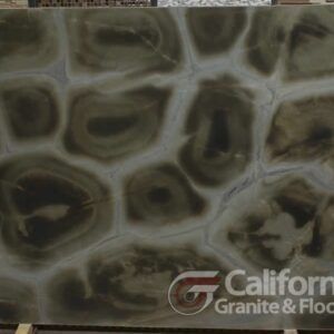 Large slab of green stone with concentric circles and grey veins; California Granite & Floors logo.