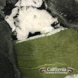 Close-up of polished stone with shades of green, black, and white. The surface is from California Granite & Flooring.