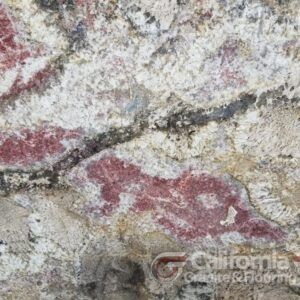 Close-up of a granite countertop with a cream background and red and black veins running through it.
