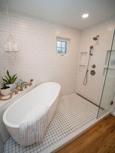 A modern bathroom featuring a white freestanding tub next to a glass-enclosed shower with subway tile and grid floor tile.