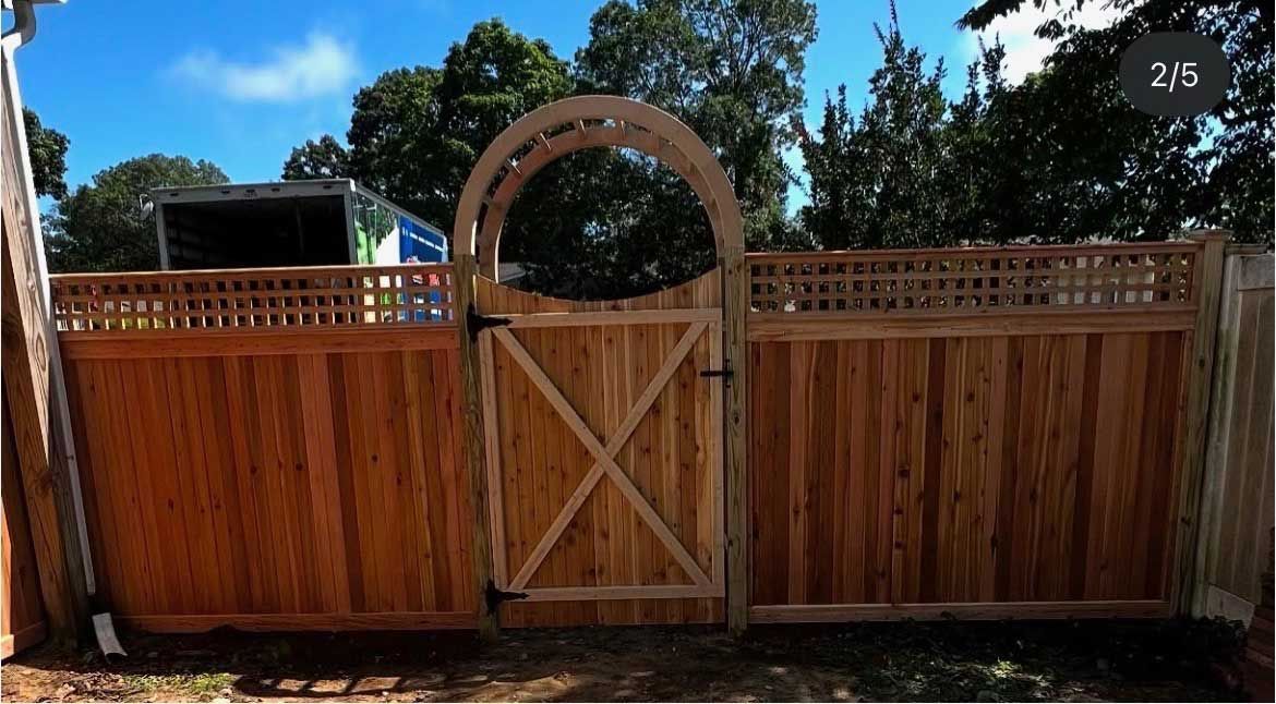 Wooden fence with gate; arched top, lattice, and x-braced gate design; blue sky.